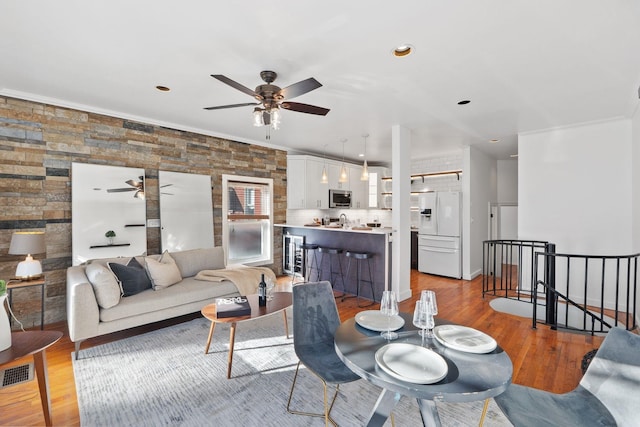 living room with ornamental molding, a ceiling fan, visible vents, recessed lighting, and light wood finished floors