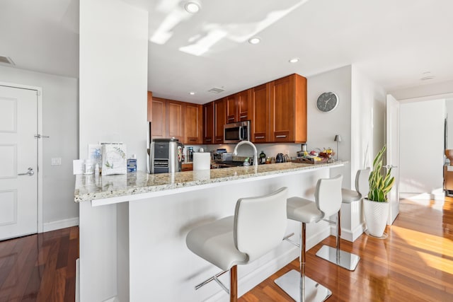 kitchen with stainless steel appliances, a breakfast bar, kitchen peninsula, and light wood-type flooring