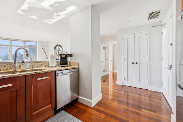 kitchen with sink, dark wood-type flooring, light stone countertops, and dishwasher