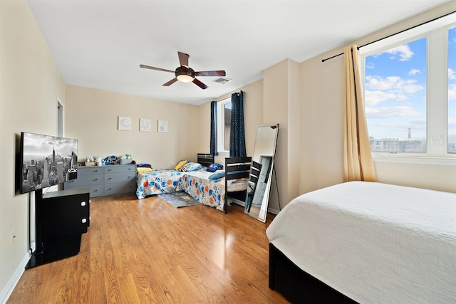 bedroom with baseboards, light wood-style flooring, visible vents, and a ceiling fan