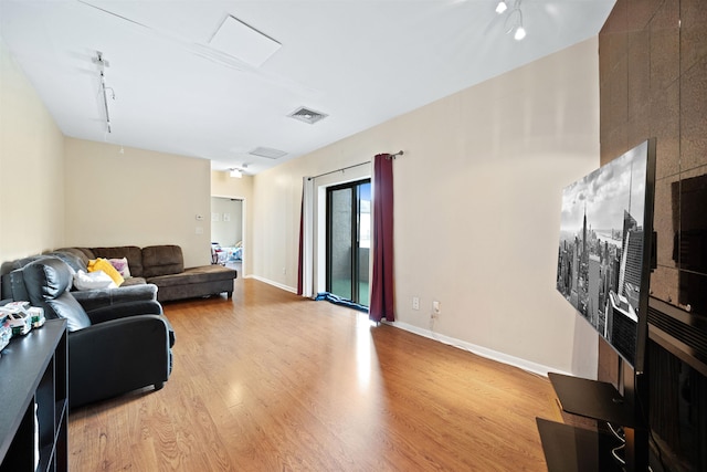 living area with wood finished floors, visible vents, and baseboards