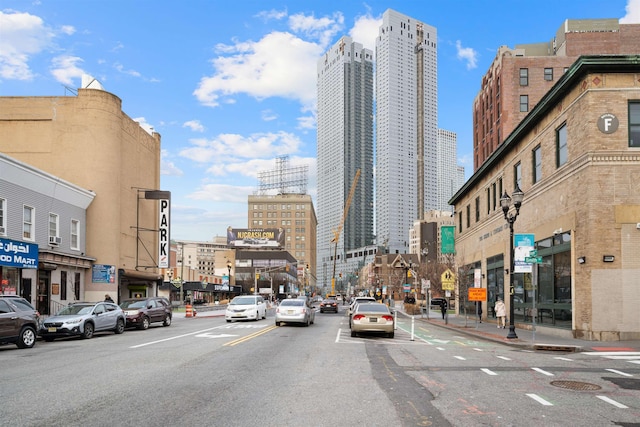 view of road with curbs, street lighting, sidewalks, and a city view