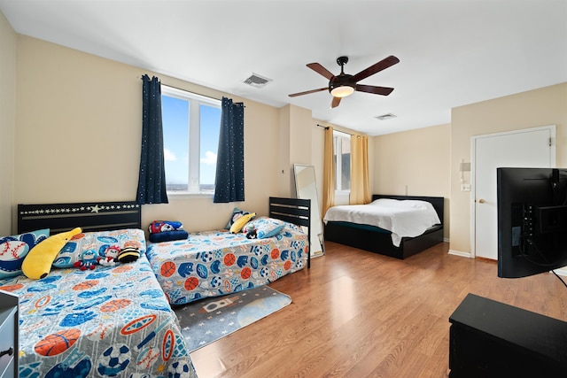 bedroom featuring visible vents, ceiling fan, baseboards, and wood finished floors