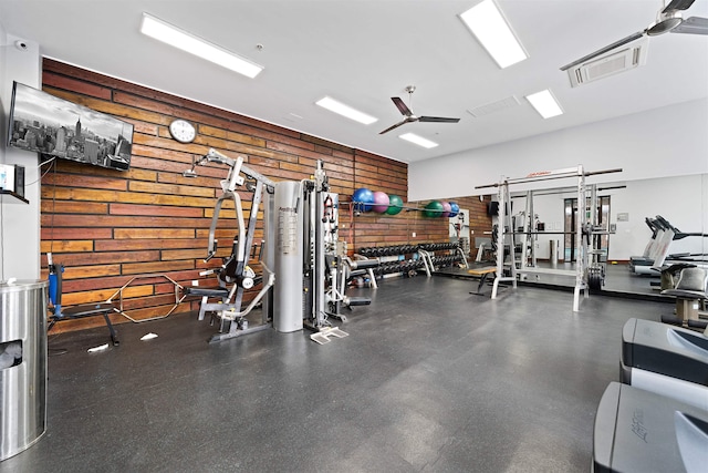 workout area with a ceiling fan, visible vents, and wooden walls