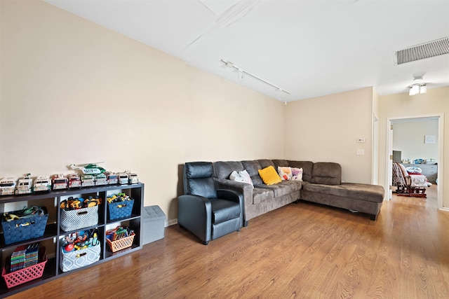 living room with wood finished floors, visible vents, and rail lighting