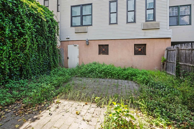view of exterior entry featuring stucco siding and fence