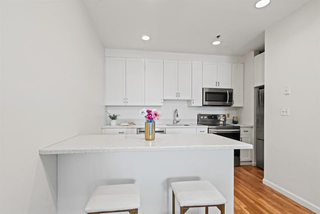kitchen with a sink, a kitchen breakfast bar, stainless steel appliances, recessed lighting, and a peninsula