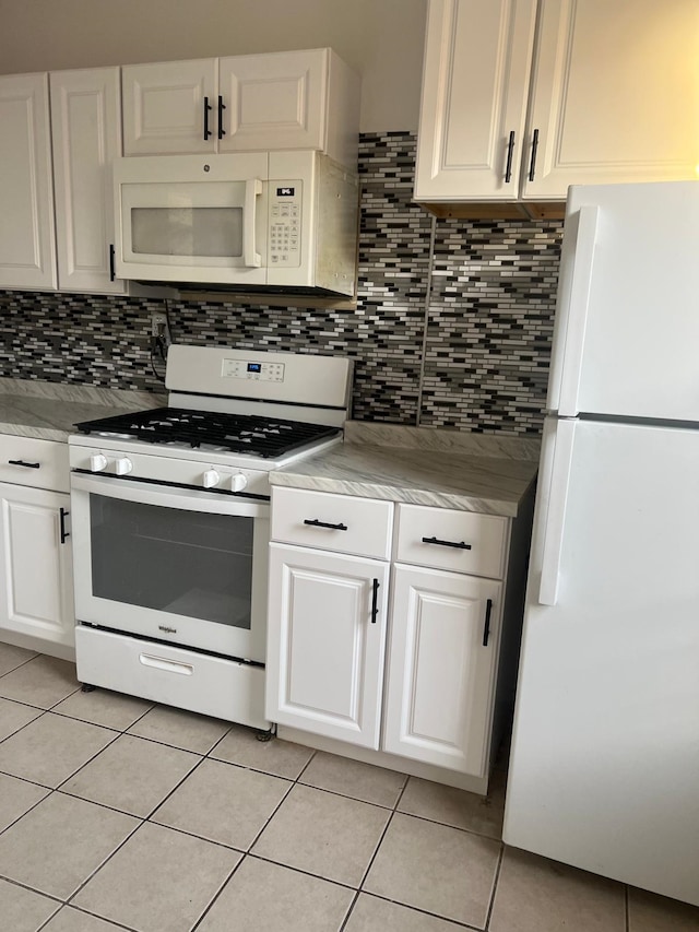 kitchen with light tile patterned floors, white appliances, tasteful backsplash, and white cabinetry