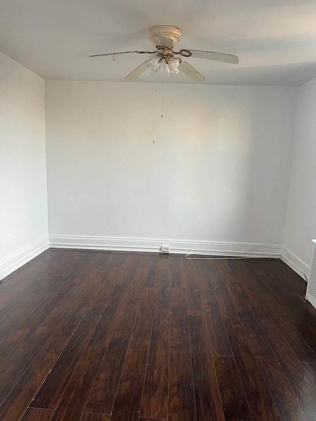 spare room featuring baseboards, a ceiling fan, and dark wood-style floors