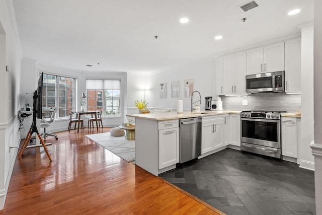501 9th St Unit 407, Hoboken, NJ 07030 - kitchen with stainless steel appliances, a peninsula, white cabinets, light countertops, and recessed lighting