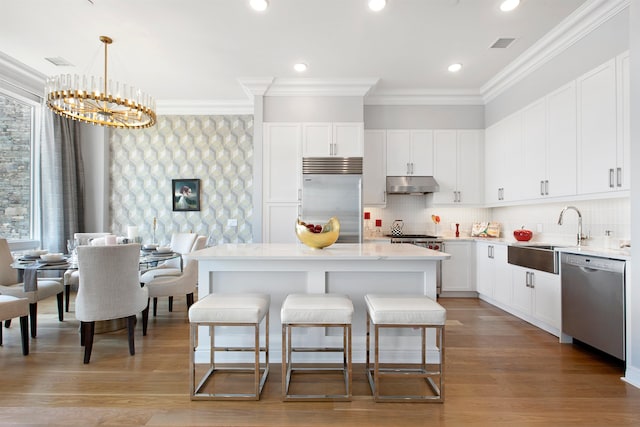 kitchen with sink, a center island, pendant lighting, white cabinets, and appliances with stainless steel finishes