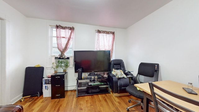 home office featuring a baseboard heating unit and wood finished floors