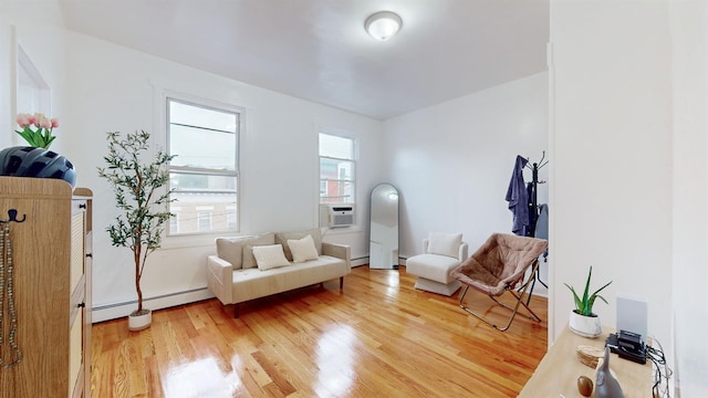 living area featuring light wood finished floors, a baseboard heating unit, and cooling unit