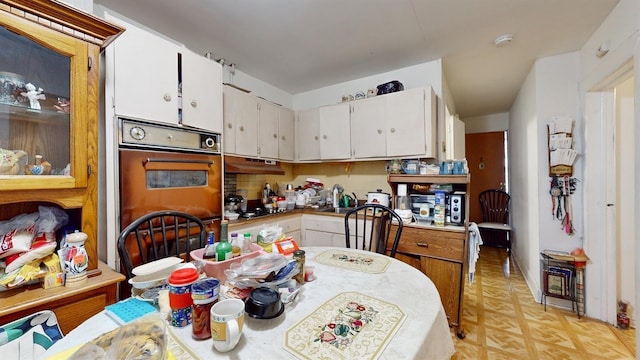kitchen featuring double oven, white cabinetry, and light floors