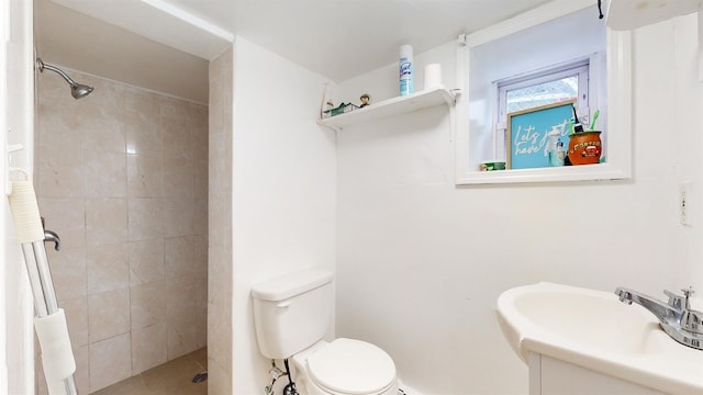 bathroom with toilet, tiled shower, and vanity