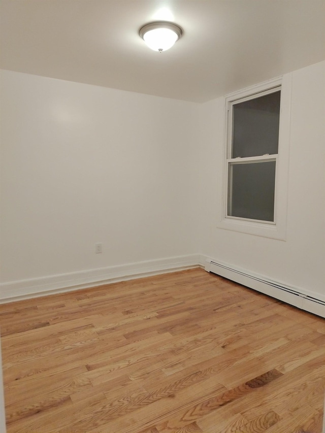 unfurnished room featuring light wood-style floors, baseboards, and a baseboard radiator