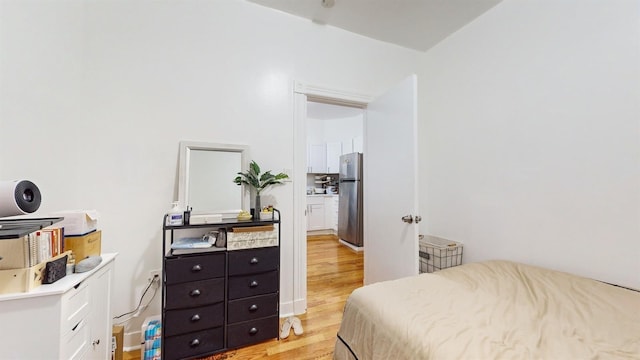 bedroom featuring light wood-style flooring and freestanding refrigerator