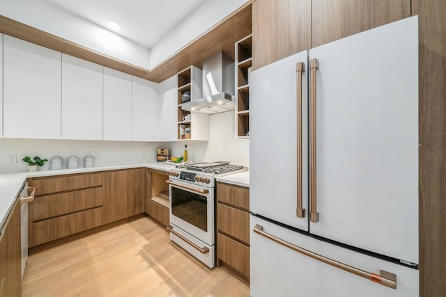 kitchen with white appliances, open shelves, white cabinets, light wood-style floors, and wall chimney exhaust hood