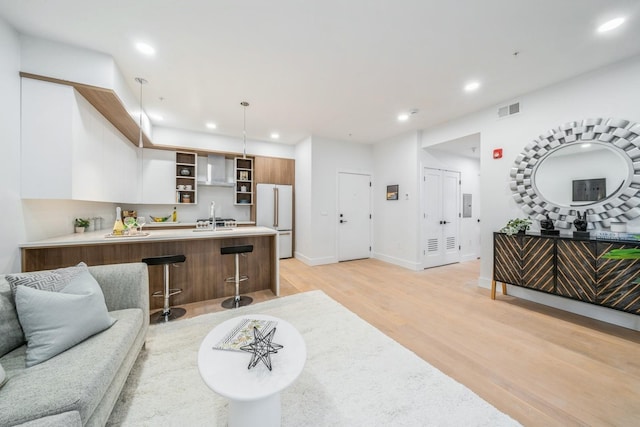 living room with light wood-type flooring, baseboards, visible vents, and recessed lighting