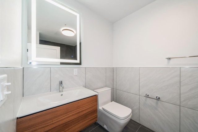 half bath with tile patterned flooring, tile walls, toilet, and vanity