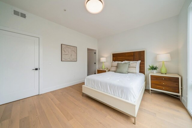 bedroom with baseboards, visible vents, and light wood finished floors