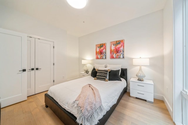 bedroom with light wood-style floors, a closet, and baseboards
