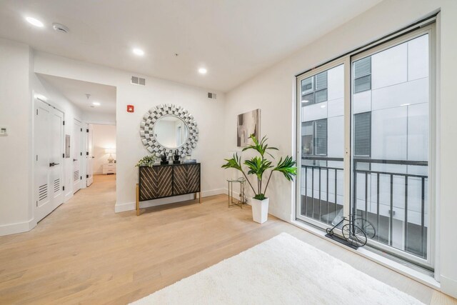 hall with recessed lighting, light wood-style flooring, baseboards, and visible vents