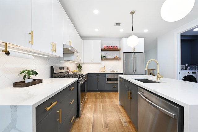 77 Clerk St Unit 1, Jersey City, NJ 07305 - kitchen featuring stainless steel appliances, a sink, open shelves, under cabinet range hood, and washer / dryer