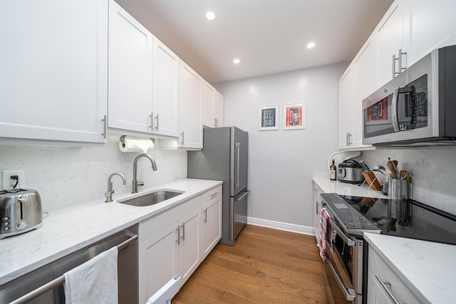 1500 Hudson St Unit 7R, Hoboken, NJ 07030 - kitchen with stainless steel appliances, decorative backsplash, white cabinets, light wood-type flooring, and recessed lighting