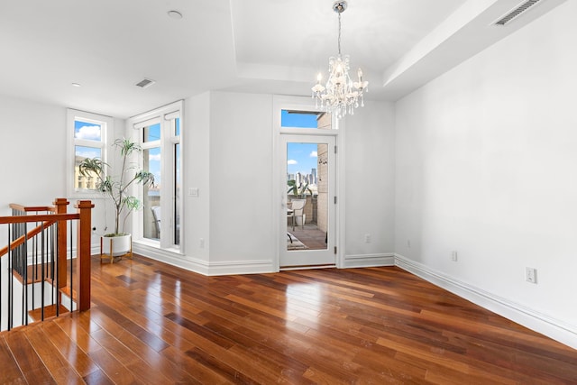 interior space featuring dark hardwood / wood-style flooring, a tray ceiling, a wealth of natural light, and an inviting chandelier