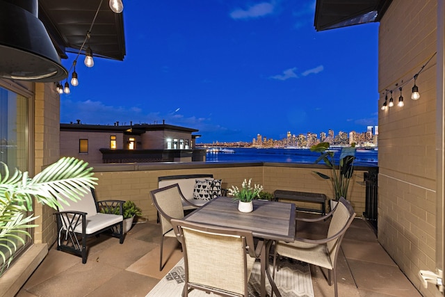 patio at night featuring a water view