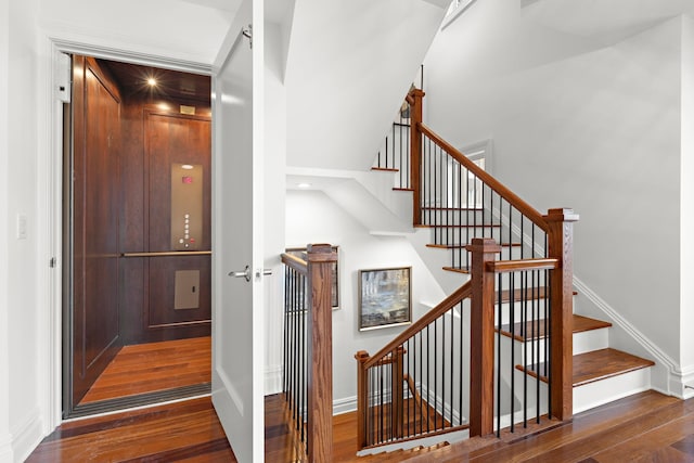 stairs with elevator and hardwood / wood-style floors