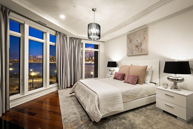 bedroom with ornamental molding, a chandelier, dark hardwood / wood-style flooring, and a tray ceiling