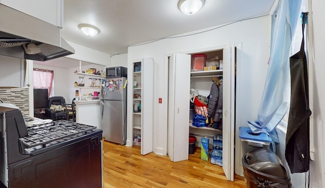 kitchen featuring light hardwood / wood-style floors, black appliances, and range hood