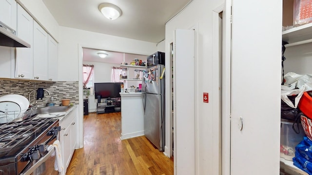 kitchen with white cabinets, light hardwood / wood-style floors, backsplash, and appliances with stainless steel finishes