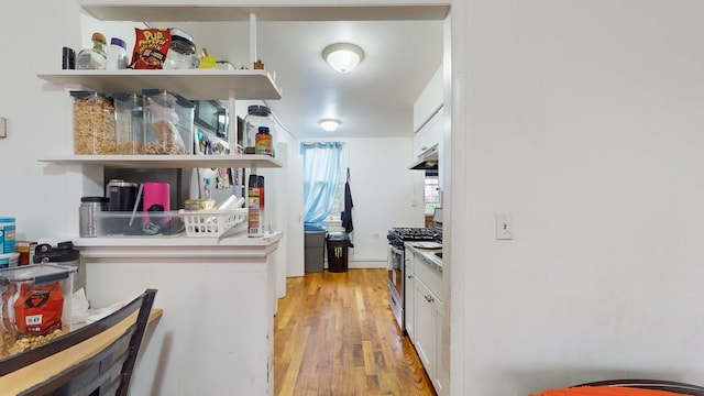 kitchen featuring white cabinetry, light hardwood / wood-style flooring, and stainless steel gas range oven