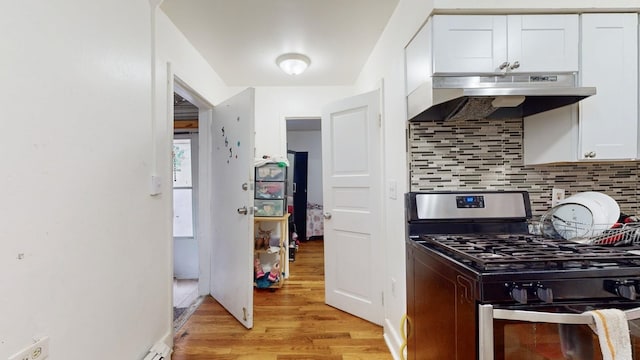 kitchen with stainless steel gas range oven, white cabinetry, backsplash, and light hardwood / wood-style floors