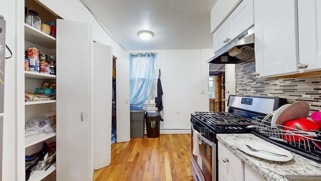 kitchen featuring stainless steel range with gas stovetop, tasteful backsplash, baseboard heating, white cabinetry, and light wood-type flooring