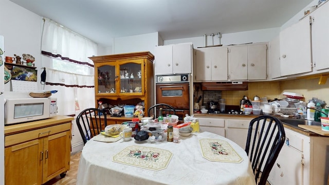 kitchen featuring sink, black oven, backsplash, gas stovetop, and white cabinets