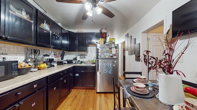 kitchen featuring light hardwood / wood-style floors, stainless steel refrigerator, light stone counters, ceiling fan, and decorative backsplash