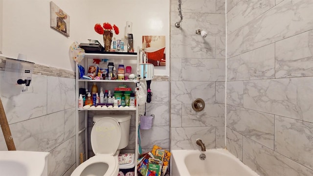 bathroom with toilet, tiled shower / bath combo, and tile walls