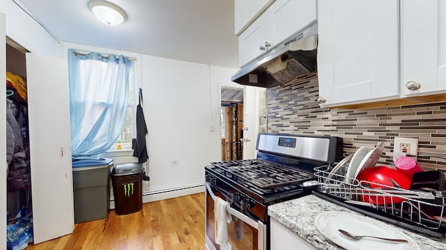 kitchen with a baseboard radiator, stainless steel gas range, light stone countertops, white cabinetry, and light hardwood / wood-style flooring