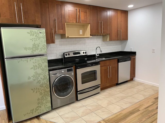 kitchen with a sink, appliances with stainless steel finishes, backsplash, brown cabinets, and washer / clothes dryer