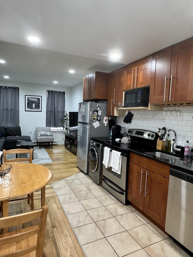 kitchen with decorative backsplash, dark countertops, open floor plan, stainless steel appliances, and a sink