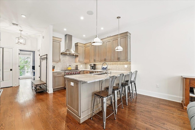 324 Hudson St # 1, Hoboken, NJ 07030 - kitchen featuring wall chimney exhaust hood, a peninsula, a kitchen bar, decorative backsplash, and a sink