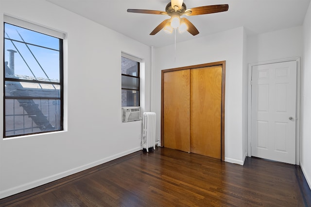 unfurnished bedroom featuring radiator, ceiling fan, a closet, and dark wood-type flooring