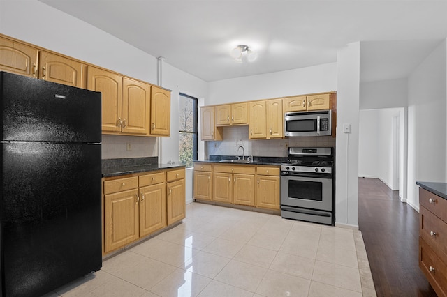 179 Manhattan Ave Unit 3B, Jersey City, NJ 07307 - kitchen with stainless steel appliances, a sink, backsplash, dark countertops, and light tile patterned floors