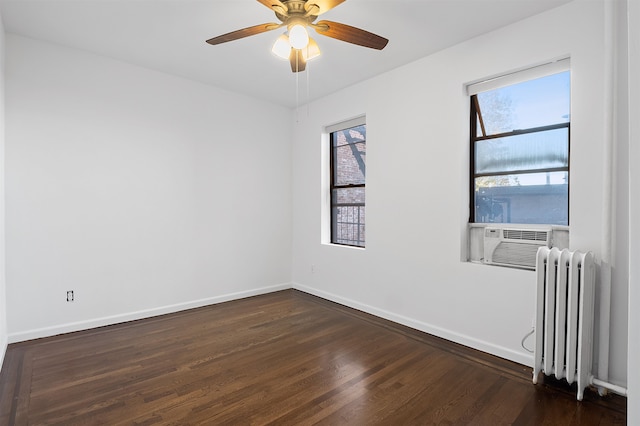 spare room featuring dark hardwood / wood-style flooring, ceiling fan, radiator heating unit, and cooling unit