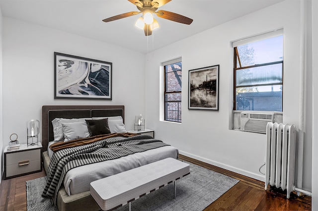 bedroom featuring ceiling fan, dark hardwood / wood-style floors, radiator heating unit, and multiple windows