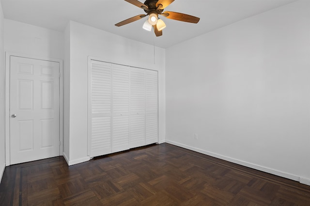 unfurnished bedroom with dark parquet floors, a closet, and ceiling fan